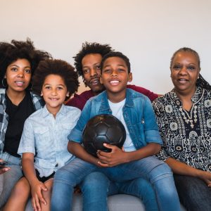 Happy african american multi-generation family watching soccer match on television in living room at home. Family and sport concept.